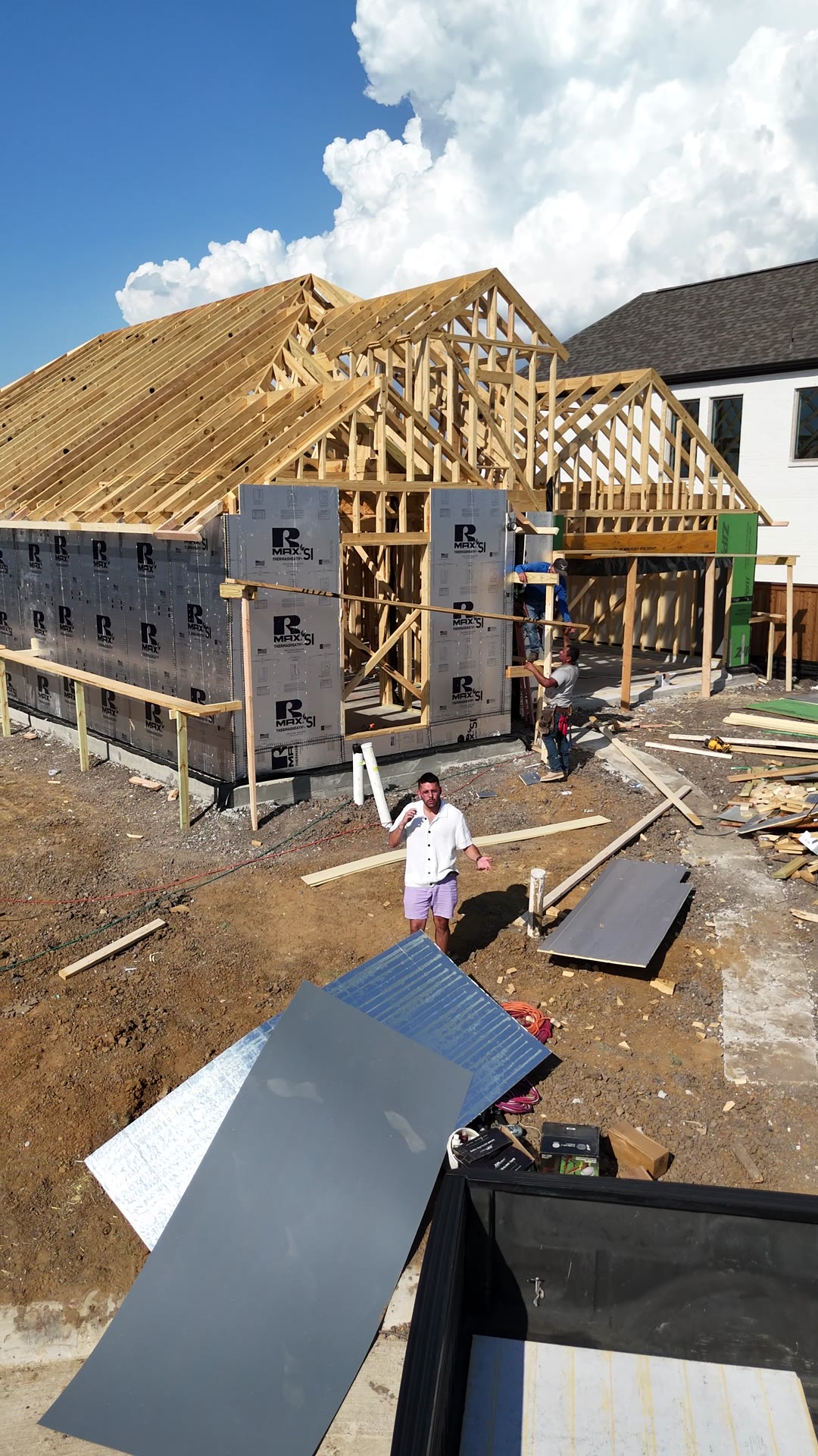 Front of the framed home with lumber and materials on the lot